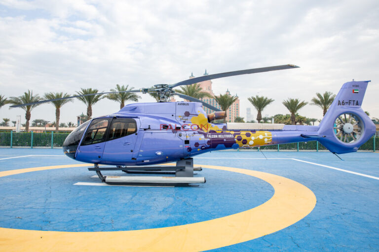 Helicopter lifting off from The Palm Helipad with a clear blue sky and luxury towers in view
