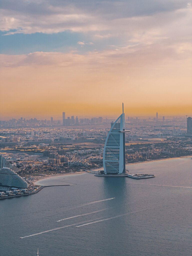 Panoramic view from helicopter showing Dubai's coastline, city, and desert meeting at the horizon